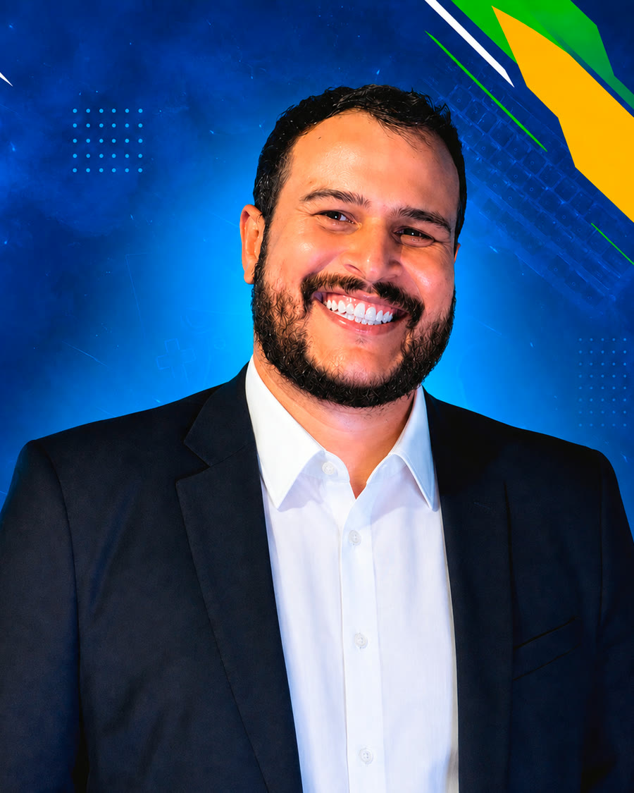 Filipe Bego sorrindo, de terno escuro e camisa branca, sobre fundo azul